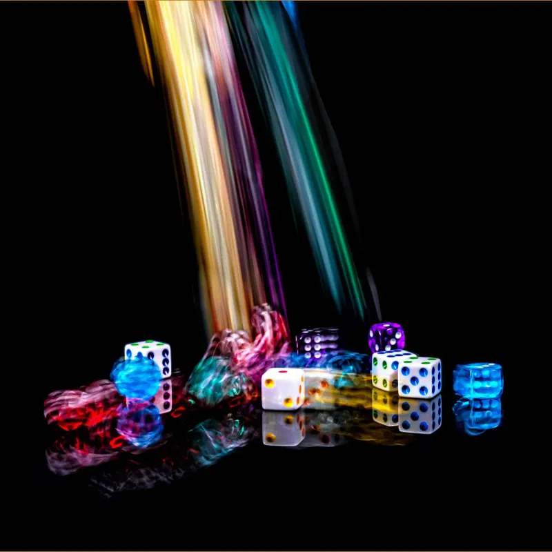 Colourful dice tumbling in streaks of light on a dark background